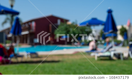 Blurred shot footage showing people relaxing and sunbathing on poolside loungers and beneath sun umbrellas, all set against the scenic background of hotel. Blurred shot footage showing people relaxing and sunbathing on poolside loungers and beneath sun umbrellas, all set against the scenic background of hotel. 108437179