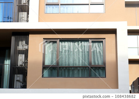 Glass window and curtain on brown wall. 108438682