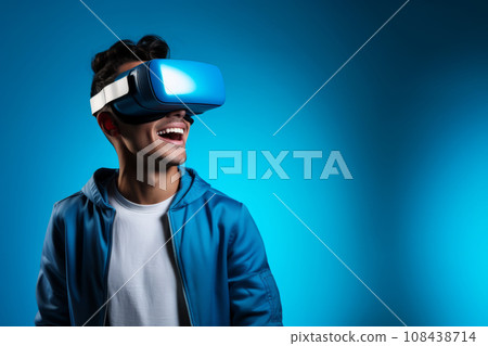 A young man wearing virtual reality glasses on a blue background. 108438714