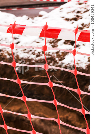 Red ribbon on construction work fence closeup 108439341