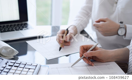 Two accountants use a calculator and tablet computer for counting taxes or revenue balance. Business, audit, and taxes concepts 108439627