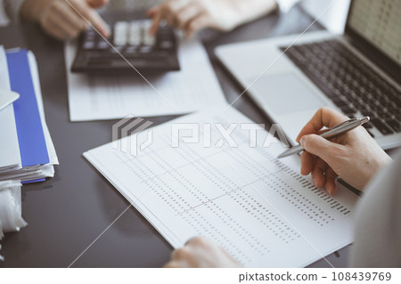 Woman accountant using a calculator and laptop computer while counting taxes for a client. Business audit concepts Woman accountant using a calculator and laptop computer while counting taxes for a client. Business audit concepts 108439769
