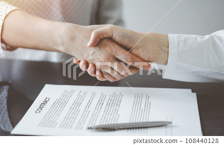 Business people signing contract papers while sitting at the glass table in office, closeup. Partners or lawyers working together at meeting. Teamwork, partnership, success concept Business people signing contract papers while sitting at the glass table in office, closeup. Partners or lawyers working together at meeting. Teamwork, partnership, success concept 108440128