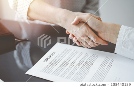 Business people signing contract papers while sitting at the glass table in office, closeup. Partners or lawyers working together at meeting. Teamwork, partnership, success concept Business people signing contract papers while sitting at the glass table in office, closeup. Partners or lawyers working together at meeting. Teamwork, partnership, success concept 108440129