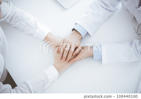 Doctor and patient sitting near each other at the table in clinic office. The focus is on female physician's hands reassuring woman, only hands, close up. Medicine concept Doctor and patient sitting near each other at the table in clinic office. The focus is on female physician's hands reassuring woman, only hands, close up. Medicine concept 108440180