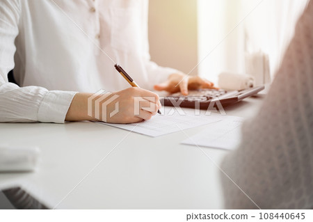 Two accountants using a laptop computer and calculator for counting taxes at white desk in office. Teamwork in business audit and finance 108440645