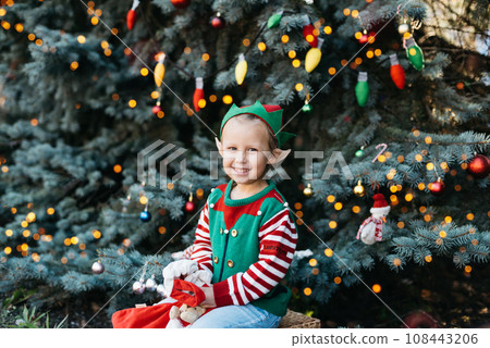 Christmas in July. children elf ears. Child waiting for Christmas in wood in july. portrait of little girl decorating Christmas tree. winter holidays and people concept. Happy Holidays. Christmas in July. children elf ears. Child waiting for Christmas in wood in july. portrait of little girl decorating Christmas tree. winter holidays and people concept. Happy Holidays. 108443206