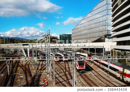 View of the Geneva Secheron railway station with many trains against the background of the cityscape and mountains. View of the Geneva Secheron railway station with many trains against the background of the cityscape and mountains. 108443439