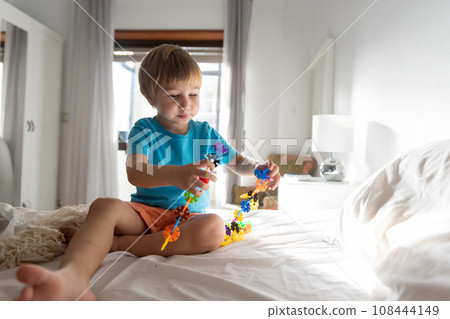 Photo of a Playful Boy on a Cozy Bed Engaged in Imaginative Play 108444149