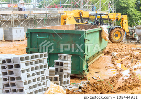 An empty dumpster for construction waste debris near construction site is loaded up with debris An empty dumpster for construction waste debris near construction site is loaded up with debris 108444911