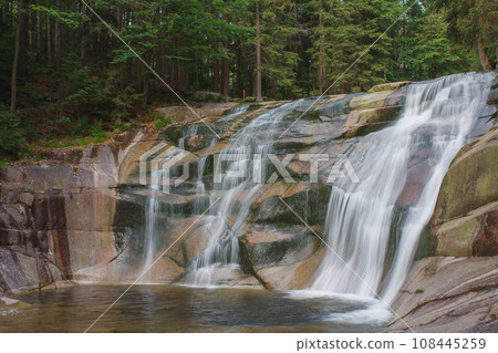 Mumlava waterfall, view from left riverside. Mountain river Mumlava, Krkonose national park, Czech Republic, summer afternoon. Mumlava waterfall, view from left riverside. Mountain river Mumlava, Krkonose national park, Czech Republic, summer afternoon. 108445259