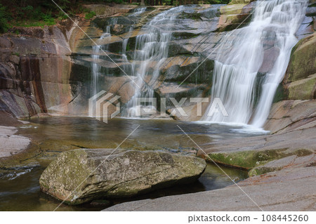 Mumlava waterfall, in the foreground granite stone. Mountain river Mumlava, Krkonose national park, Czech Republic, summer afternoon. 108445260