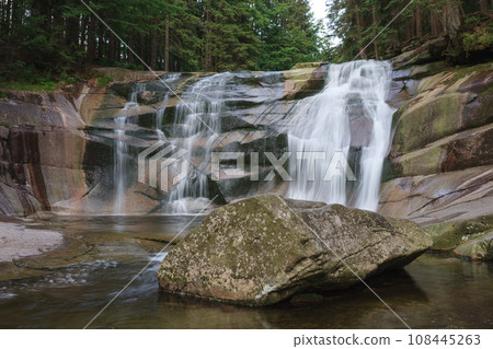 Mumlava waterfall, in the foreground granite stone. Mountain river Mumlava, Krkonose national park, Czech Republic, summer afternoon. Mumlava waterfall, in the foreground granite stone. Mountain river Mumlava, Krkonose national park, Czech Republic, summer afternoon. 108445263