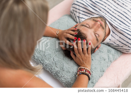 Woman healer performing access bars to a man, an alternative medicine concept 108445418