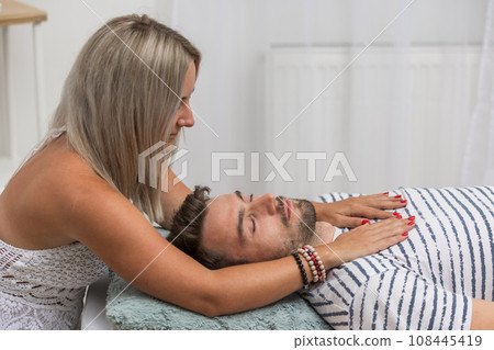 Woman healer performing access bars to a man, an alternative medicine concept 108445419