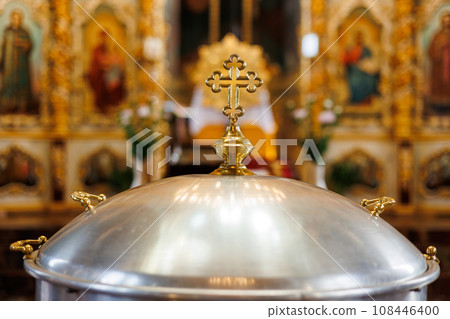 Aluminium church font, large bowl, with golden cross and saint water for the baptism of babies in Orthodox Church temple, Christening ceremony.Concept of rituals, sacraments of the Christian religion. 108446400