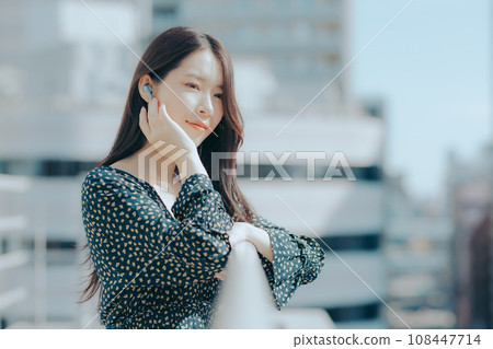 Young woman listening to music with earphones on the rooftop 108447714