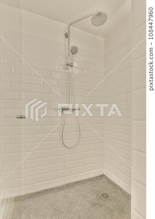 a bathroom with white tiles on the wall and shower head mounted to the wall in front of the bathtub 108447960