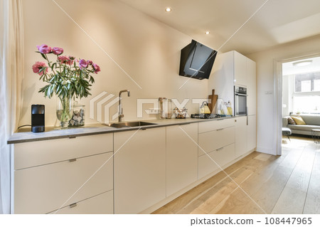 a kitchen with flowers on the counter and tv mounted to the wall in the living room next to the dining area a kitchen with flowers on the counter and tv mounted to the wall in the living room next to the dining area 108447965