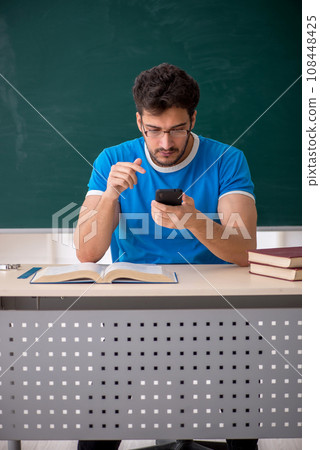 Young male student holding smartphone in the classroom 108448425