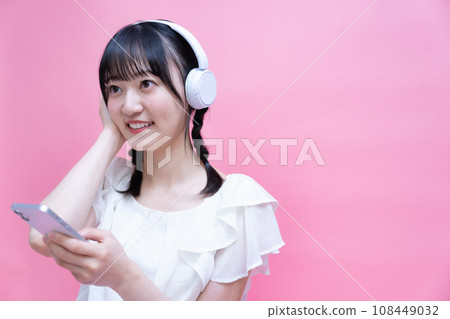 Young woman listening to music on smartphone with headphones Young woman listening to music on smartphone with headphones 108449032