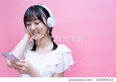Young woman listening to music on smartphone with headphones 108449033