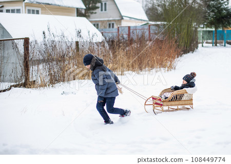 Boy pulling his friend on a sledge 108449774
