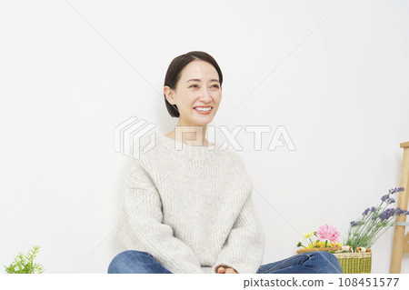 Portrait of a smiling woman sitting in the living room 108451577