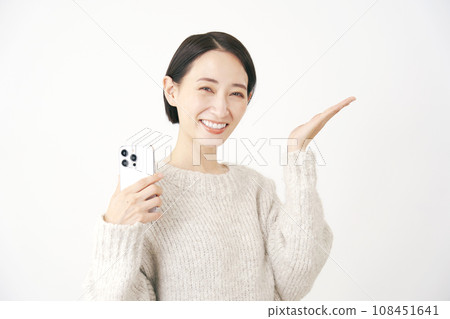 A woman holding a smartphone and pointing to the right side with her palm, white background A woman holding a smartphone and pointing to the right side with her palm, white background 108451641