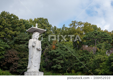 Mireuk Daebul statue of the bodhisattva Maitreya at Bongeunsa Temple, a Buddhist temple in Seoul. With background of autumn leaves. It is the tallest stone statue in Korea. 108452010
