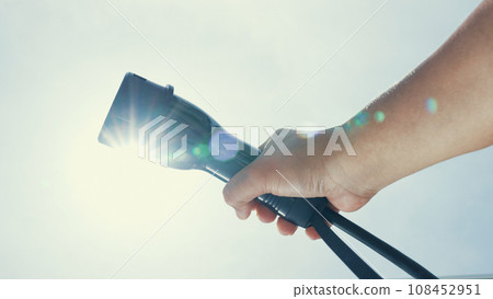 Closeup hand grasping an EV plug for electric vehicle as progressive idea. 108452951