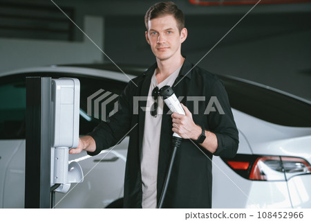 Young man travel with EV electric car to shopping center parking lot innards Young man travel with EV electric car to shopping center parking lot innards 108452966