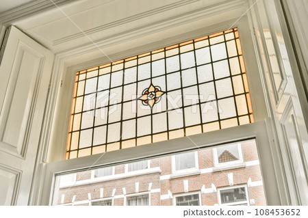 a stained glass window in a house with white trim on the windowsills, and a brick wall behind it a stained glass window in a house with white trim on the windowsills, and a brick wall behind it 108453652
