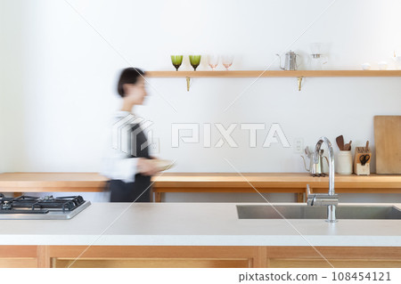 A woman walking in the kitchen 108454121
