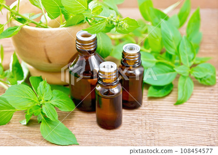 Oil with basil and mortar on wooden board 108454577