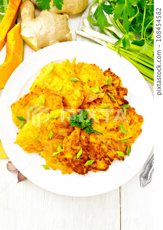 Pancakes of pumpkin with cheese in white plate on board top 108454582