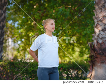 idea of healthy lifestyle and sports in a modern city. Female jogger. Fit young Caucasian woman stretching muscle in park before running and enjoying healthy outdoor. Fitness girl in public park. 108455314