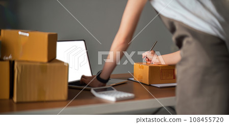 Closeup woman Asian is writing a list of customer on paper before shipping to them, she runs an ecommerce business on websites and social media Closeup woman Asian is writing a list of customer on paper before shipping to them, she runs an ecommerce business on websites and social media 108455720