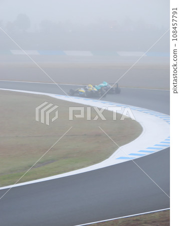 Formula car race on a foggy circuit in autumn Formula car race on a foggy circuit in autumn 108457791