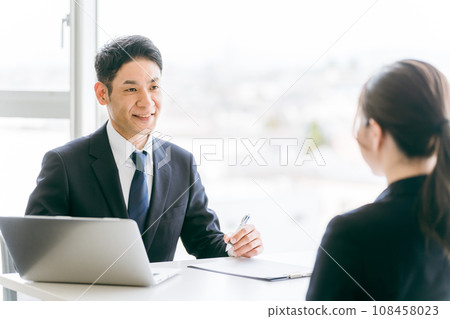 提供解釋、諮詢和指導的西裝商人和傾聽談話的女商人 提供解釋、諮詢和指導的西裝商人和傾聽談話的女商人 108458023