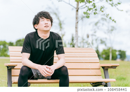 Asian man resting on a park bench during exercise (deep breathing, muscle pain, overtraining syndrome) Asian man resting on a park bench during exercise (deep breathing, muscle pain, overtraining syndrome) 108458441