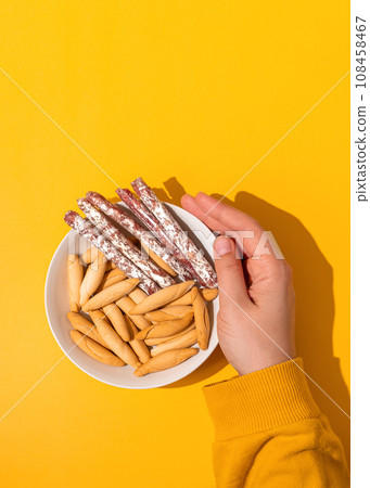 Hand holding bowl with mini fuet and bread sticks Hand holding bowl with mini fuet and bread sticks 108458467