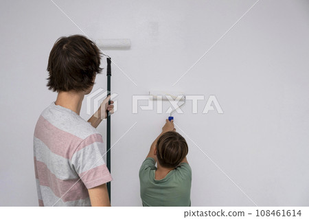 children paint the wall with a roller. teenagers spend time together helping to make repairs. 108461614