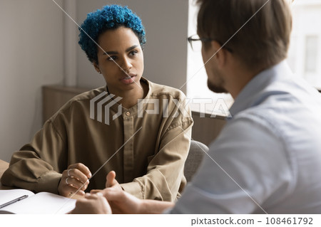 Serious young African American professional talking to male colleague 108461792