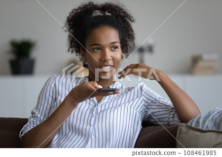 Happy millennial teen Black girl speaking at smartphone speakerphone Happy millennial teen Black girl speaking at smartphone speakerphone 108461985