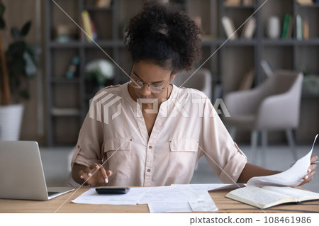 Focused African American millennial woman checking papers for payment Focused African American millennial woman checking papers for payment 108461986