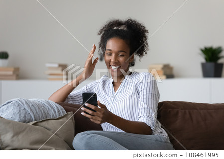 Happy joyful millennial Black girl making video call on smartphone Happy joyful millennial Black girl making video call on smartphone 108461995