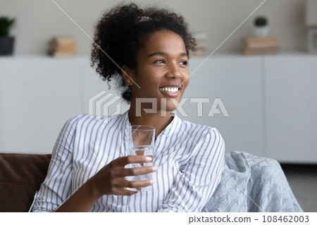 Happy young African woman, millennial girl holding glass of water 108462003
