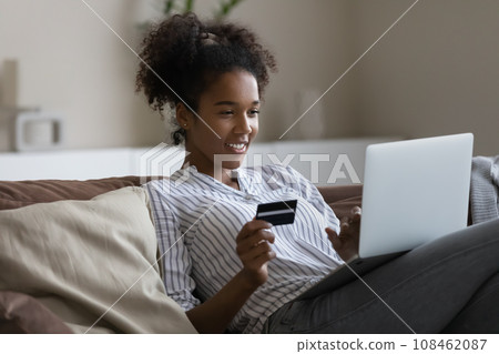 Happy shopaholic girl with laptop using credit card for shopping 108462087