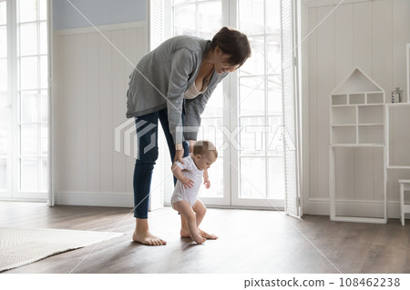 Toddler holding loving mom hands and makes first steps 108462238